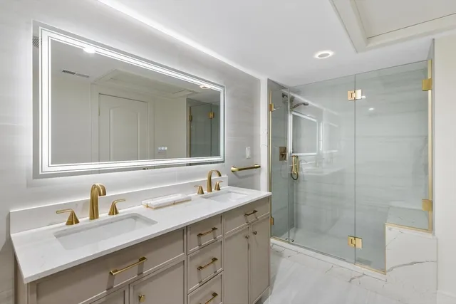 a bathroom with a shower sink double vanity and mirror