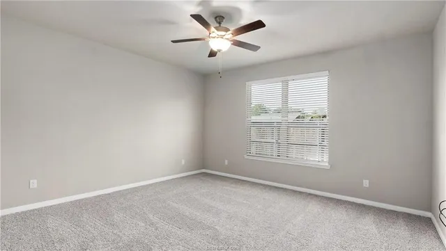 an empty room with windows and ceiling fan