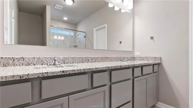 a bathroom with a granite countertop sink and a mirror