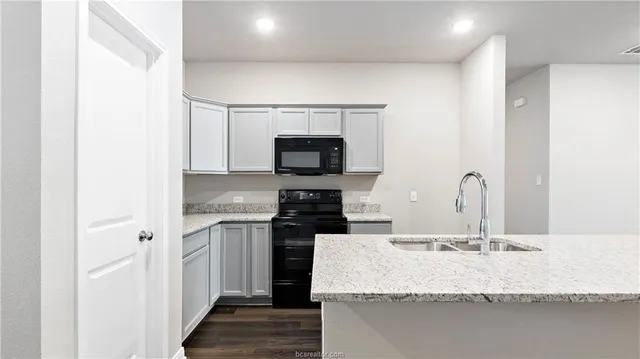 a kitchen with granite countertop a sink and a stove top oven with wooden floor