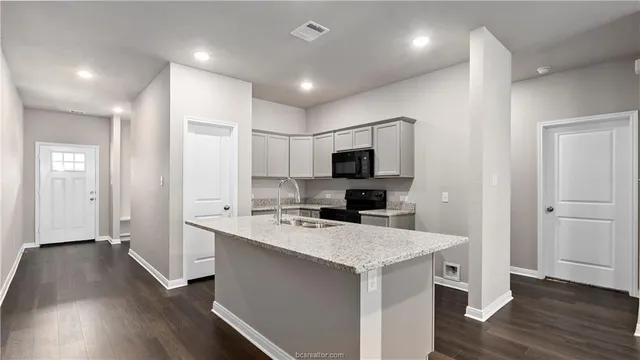 a kitchen with a sink a counter top space stainless steel appliances and wooden floor