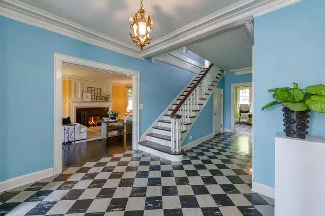 a living room with a black white checkered floor with couches and a dining table with wooden floor