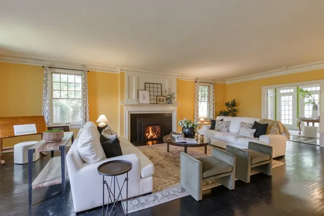 a living room with furniture a fireplace and large windows