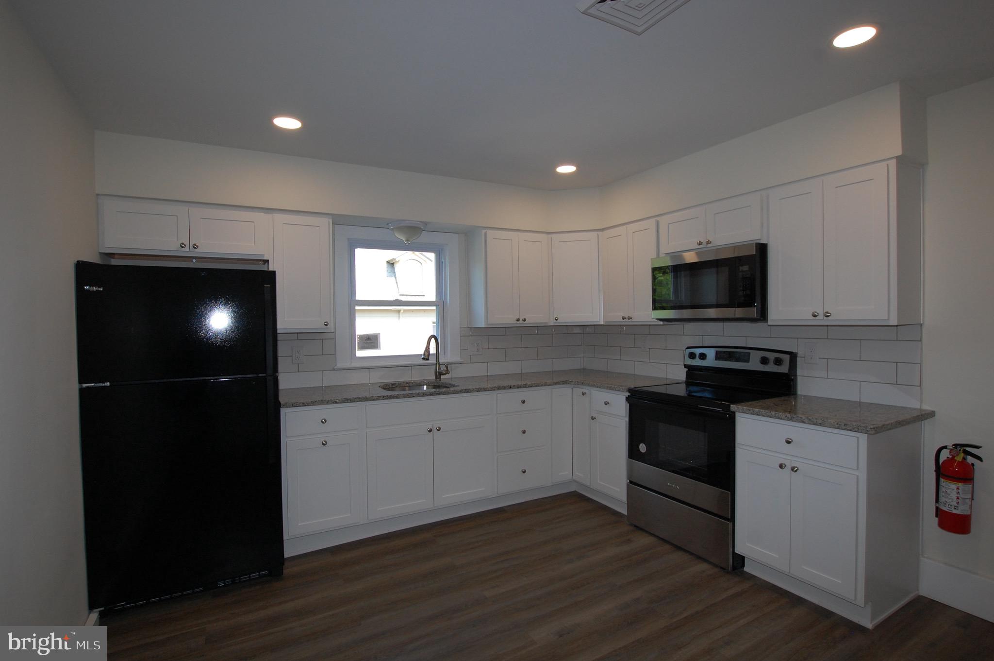 35 East Avenue, Unit 2 Woodstown, NJ 08098 - Photo 2 of 10 a kitchen with granite countertop a stove a sink and a microwave