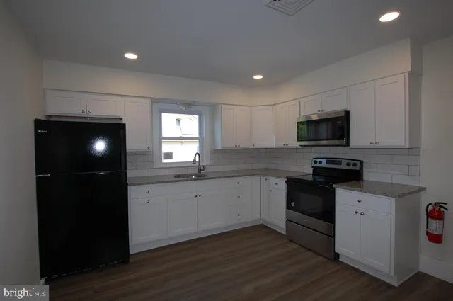 a kitchen with granite countertop a stove a sink and a microwave