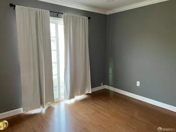an empty room with wooden floor and windows with curtains