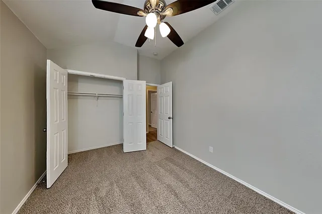 a view of an empty room and chandelier fan