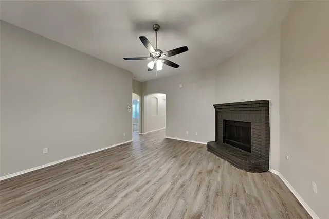 an empty room with wooden floor fan and a ceiling fan