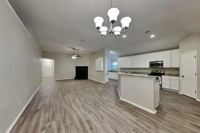a view of a kitchen with a sink wooden cabinets and a chandelier