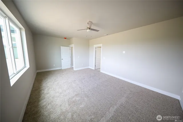 an empty room with windows and ceiling fan