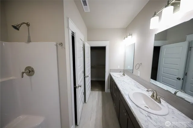 a bathroom with a granite countertop tub sink and mirror