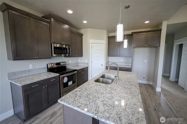 a kitchen with kitchen island granite countertop stainless steel appliances and wooden cabinets