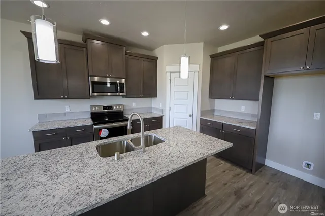 a kitchen with stainless steel appliances granite countertop a sink refrigerator and microwave
