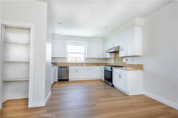 a large kitchen with a white stove top oven and white cabinets