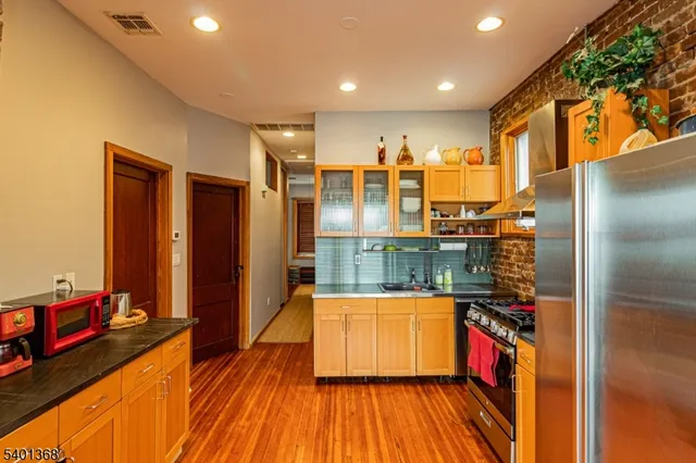 a view of a living room with stainless steel appliances wooden floor and a large window