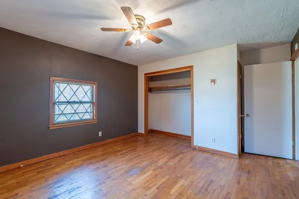 a view of an empty room with window and wooden floor