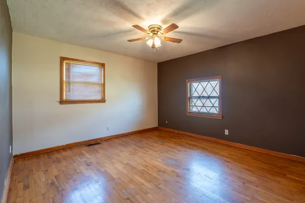 a view of an empty room with window and wooden floor