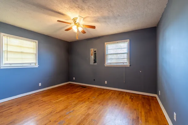 a view of an empty room with wooden floor and a window