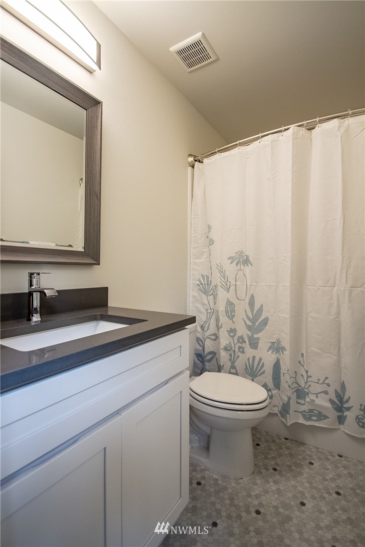16716 Erickson Road Southwest Longbranch, WA 98351 - Photo 11 of 17 a bathroom with a granite countertop sink a toilet and a mirror