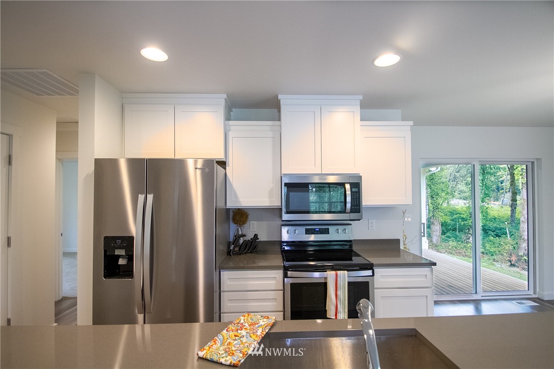 16716 Erickson Road Southwest Longbranch, WA 98351 - Photo 3 of 17 a kitchen with stainless steel appliances a refrigerator a stove a sink dishwasher a oven with a dining table and chairs
