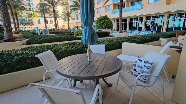 a view of a patio with table and chairs potted plants and large tree