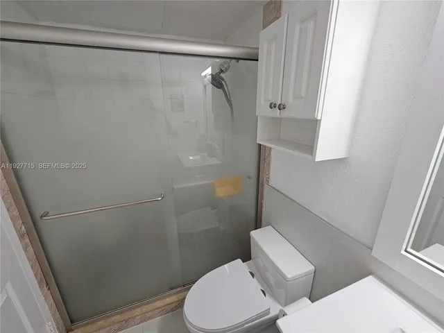 a white toilet sitting next to a shower