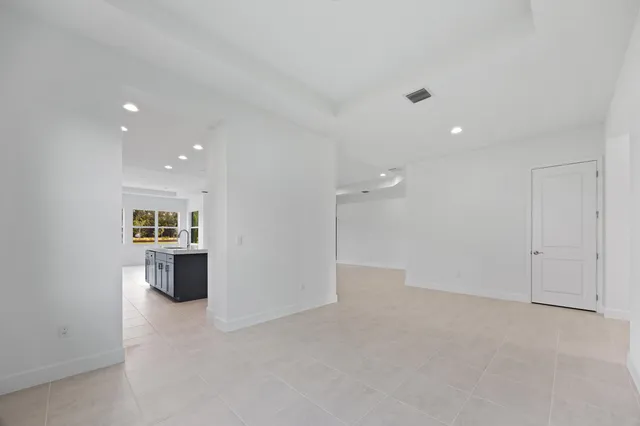 a large white kitchen with stainless steel appliances a large counter top a stove and a refrigerator