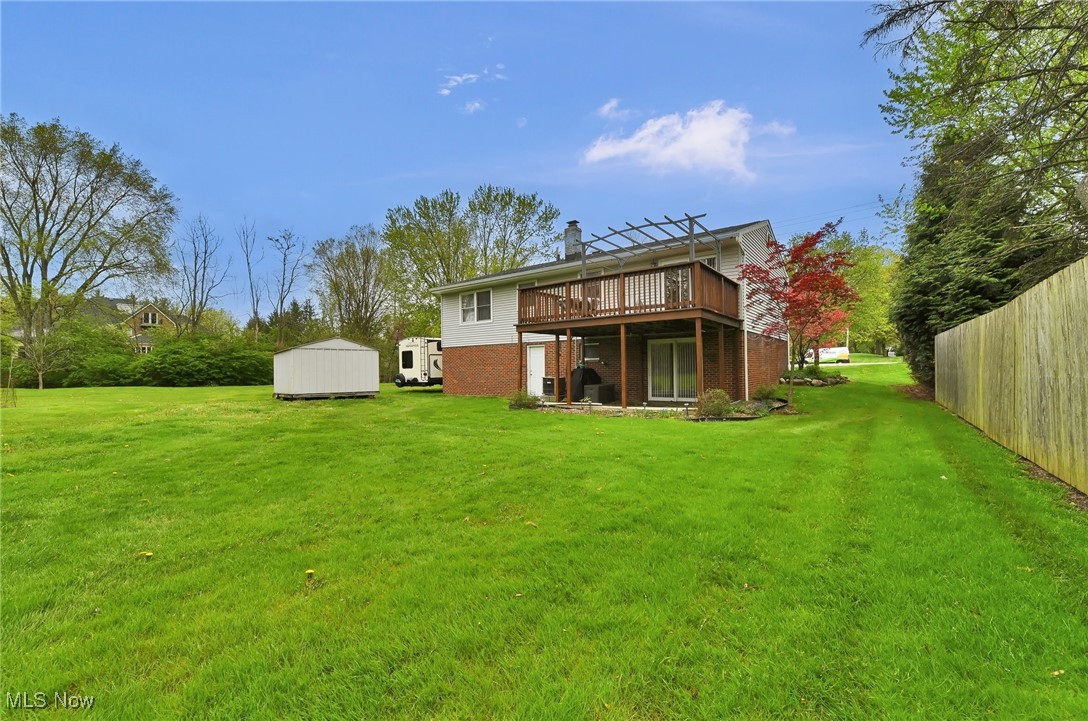 7676 Brecksville Road Independence, OH 44131 - Photo 24 of 32 Back of property with a storage shed, brick siding, a lawn, and a deck