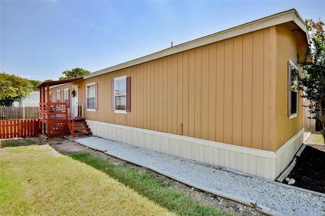 a view of a backyard with wooden fence and a large tree