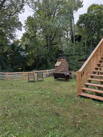 a view of a backyard with wooden fence and large trees