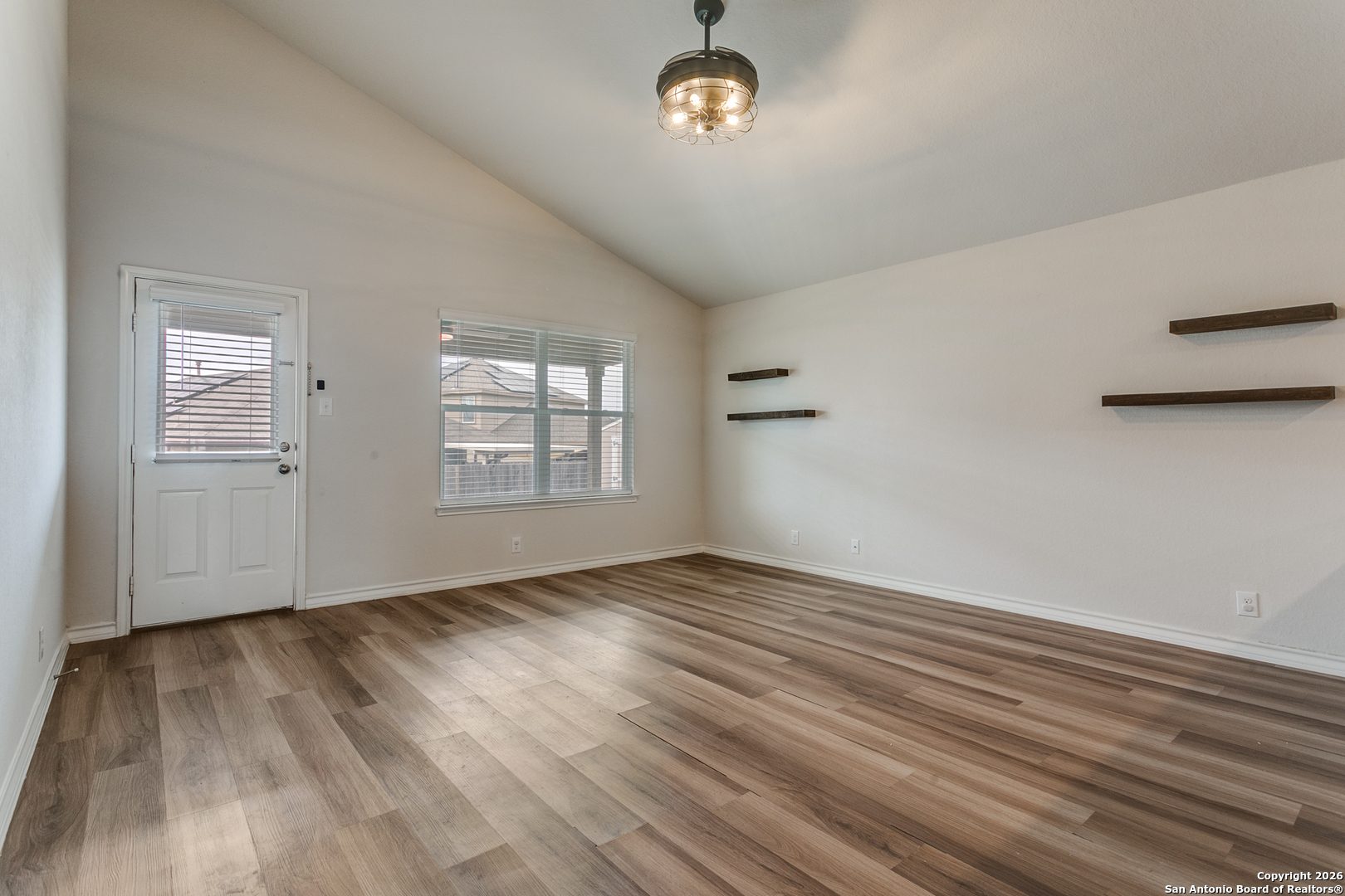 2615 Yaupon Ranch San Antonio, TX 78244 - Photo 12 of 25 an empty room with wooden floor chandelier and windows