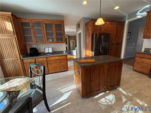 a kitchen with stainless steel appliances granite countertop wooden cabinets a sink a stove a dining table and chairs