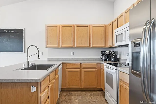 a kitchen with stainless steel appliances granite countertop a sink stove refrigerator and cabinets