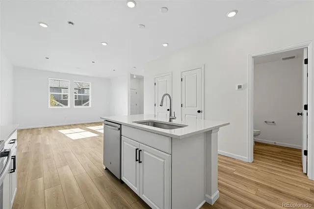 a kitchen with stainless steel appliances a stove top oven a sink a refrigerator white cabinets and wooden floor