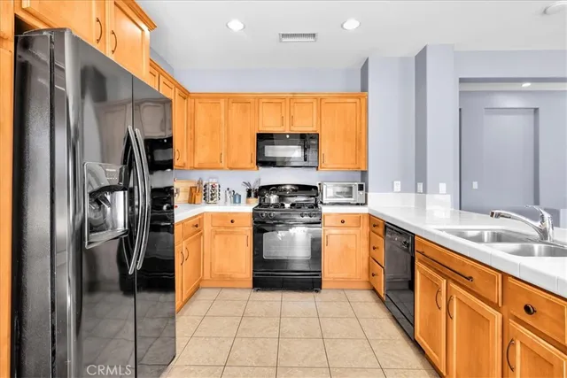 a kitchen with stainless steel appliances granite countertop a refrigerator a stove and a sink