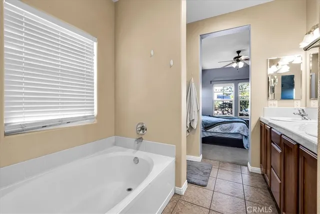 a en suite spacious bathroom with a tub double vanity and window