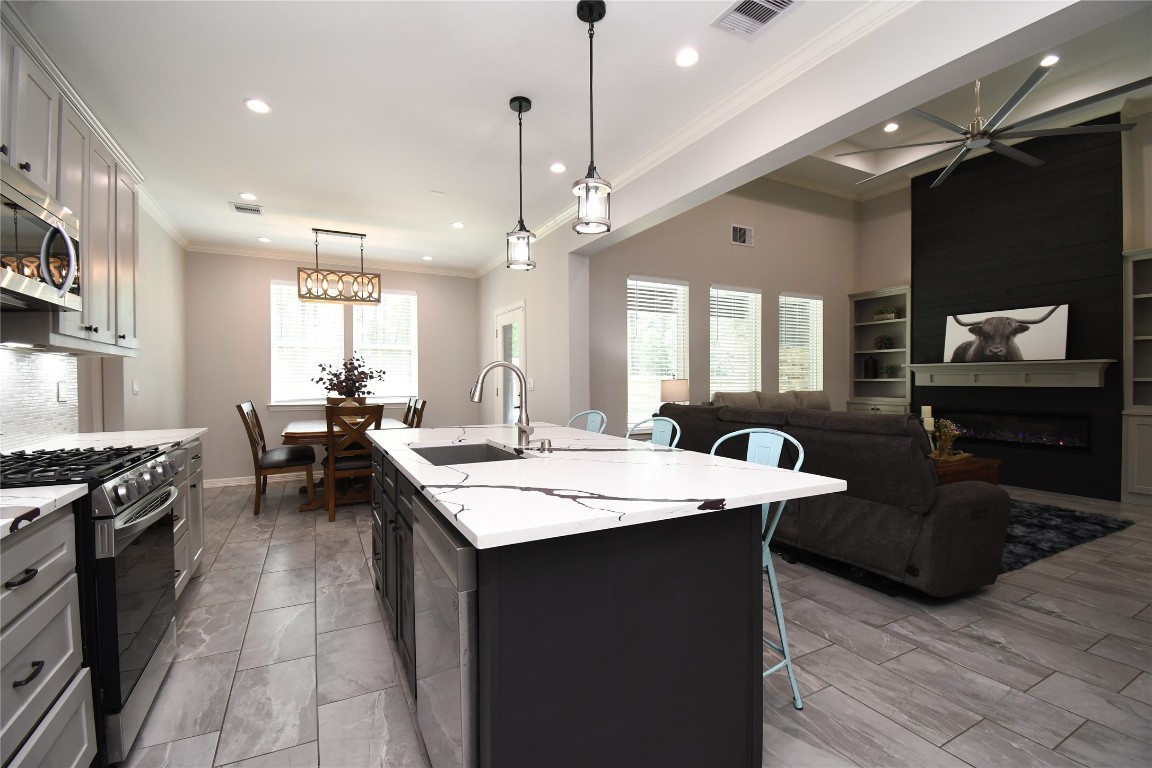 2406 Hummingbird Street New Caney, TX 77357 - Photo 14 of 40 a large kitchen with a counter space a sink appliances and living room view