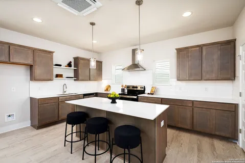 a kitchen with stainless steel appliances granite countertop a sink a stove a refrigerator and island with wooden floor