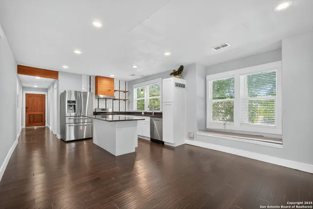 an open kitchen with white cabinets and refrigerator