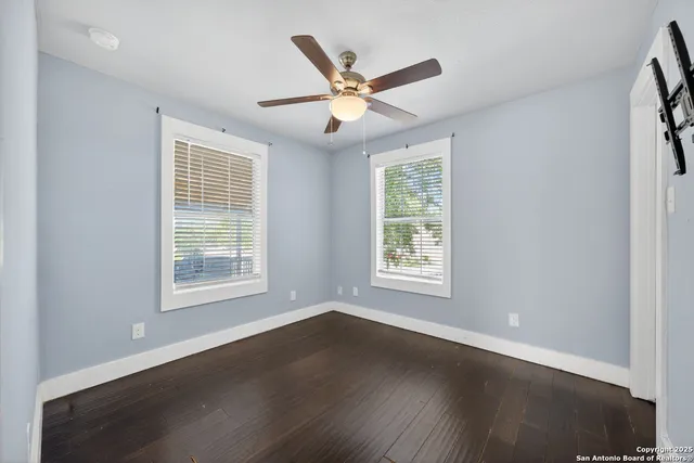 an a room with wooden floor a ceiling fan and a window