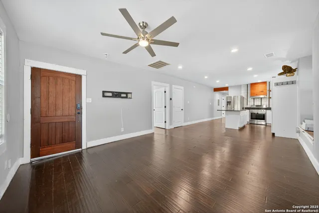 a view of an empty room with wooden floor and a window