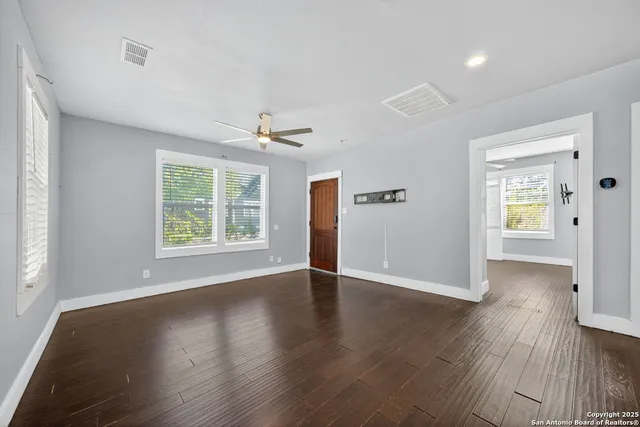 an empty room with wooden floor and windows