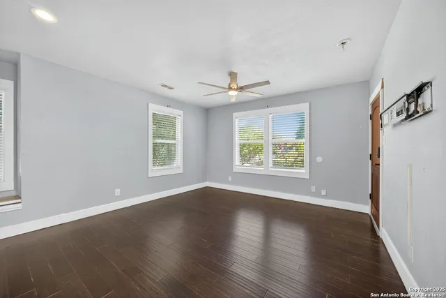 an empty room with wooden floor and windows
