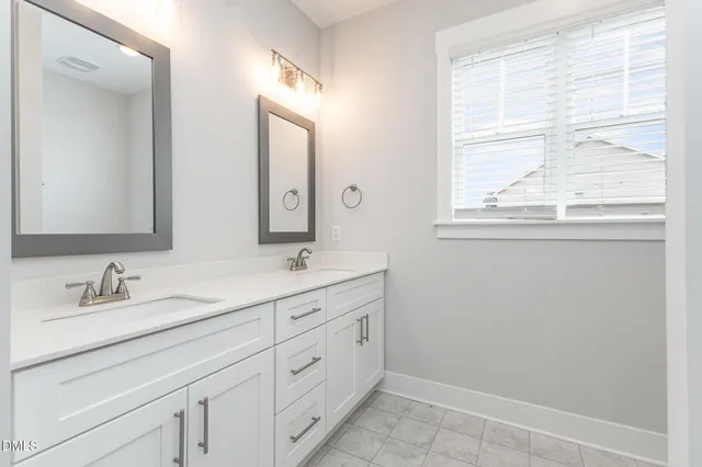 a bathroom with double sink and a window