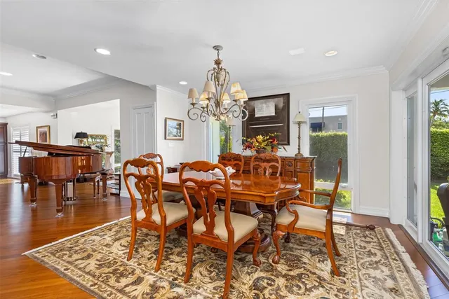 a dining room with wooden floor a chandelier a wooden table and chairs