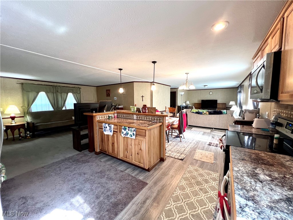 2986 Southeast Branch Road Southwest Malta, OH 43758 - Photo 41 of 41 Kitchen with open floor plan, appliances with stainless steel finishes, dark countertops, hanging light fixtures, and a textured ceiling