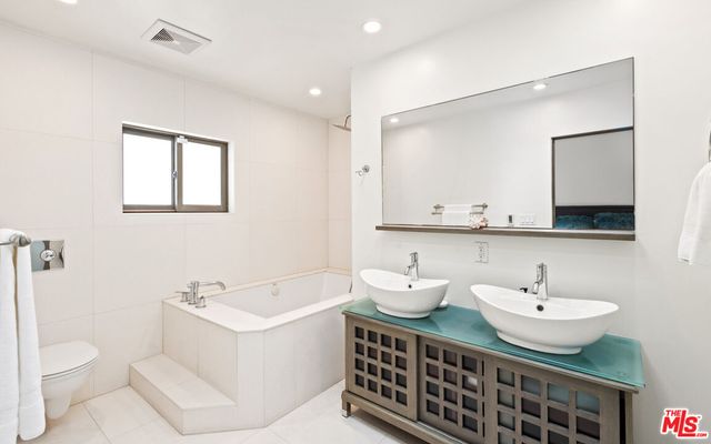 a large white bed in a bedroom next to a window