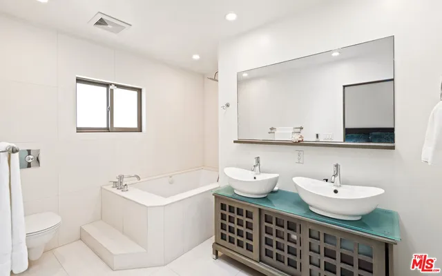 a large white bed in a bedroom next to a window