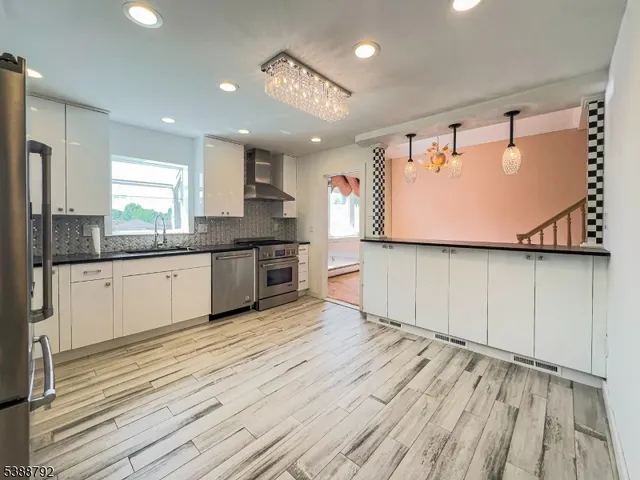 a large kitchen with stainless steel appliances granite countertop a lot of counter space and wooden floors