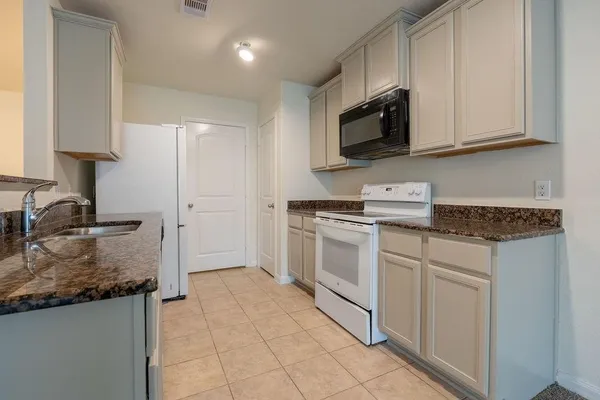 a kitchen with granite countertop white cabinets and white appliances